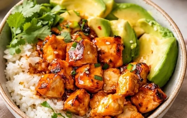 Delicious hot honey chicken bowls garnished with vegetables and sesame seeds.