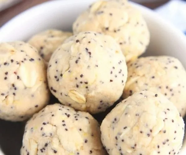 Lemon poppy seed energy bites arranged on a plate with a zestful garnish.