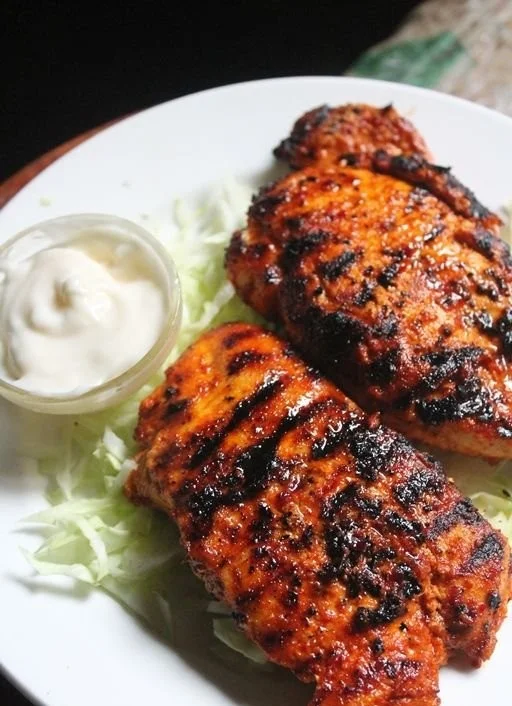 Spicy grilled chicken breast served on a plate with herbs