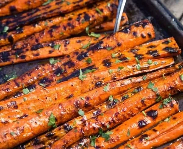 Plate of grilled and glazed carrots garnished with herbs