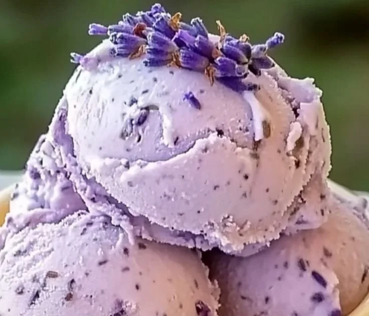 Delicious honey lavender ice cream in a cone topped with lavender flowers.
