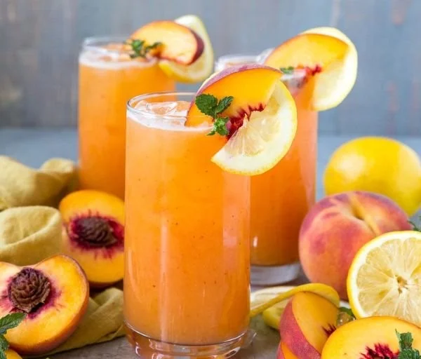 Refreshing glass of Peach Lemonade with slices of peach and lemon