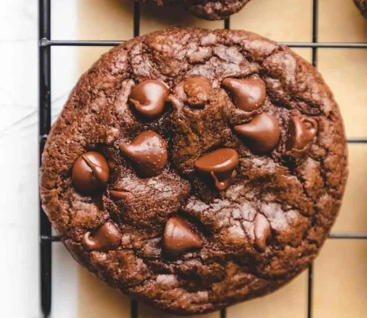 Delicious chewy chocolate chip cookies on a baking tray with melted chocolate.