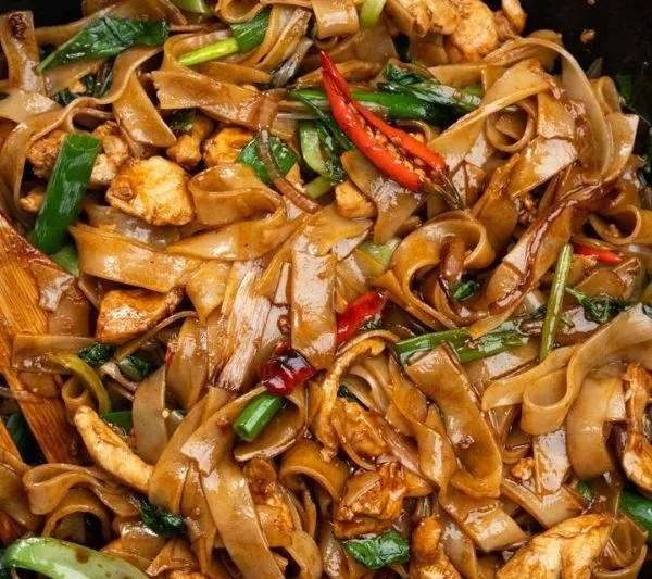 Plate of flavorful drunken noodles with colorful vegetables and spices