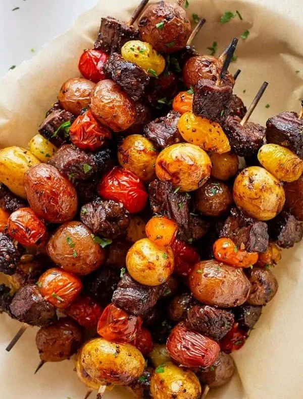 Delicious grilled rosemary garlic steak kebabs on skewers with fresh herbs