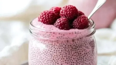 Maple-sweetened raspberry chia pudding in a glass, topped with fresh berries.