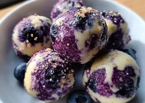 Mini berry cheesecake bites topped with fresh berries on a white plate