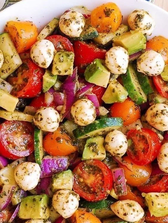 Tomato Cucumber Avocado Salad with mozzarella and pesto on a plate