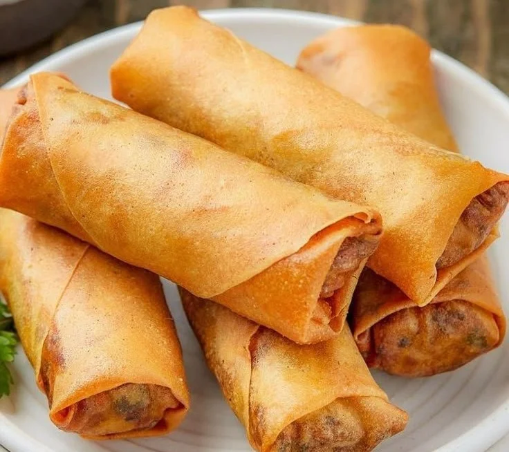 Crispy air fryer spring rolls on a plate with dipping sauce