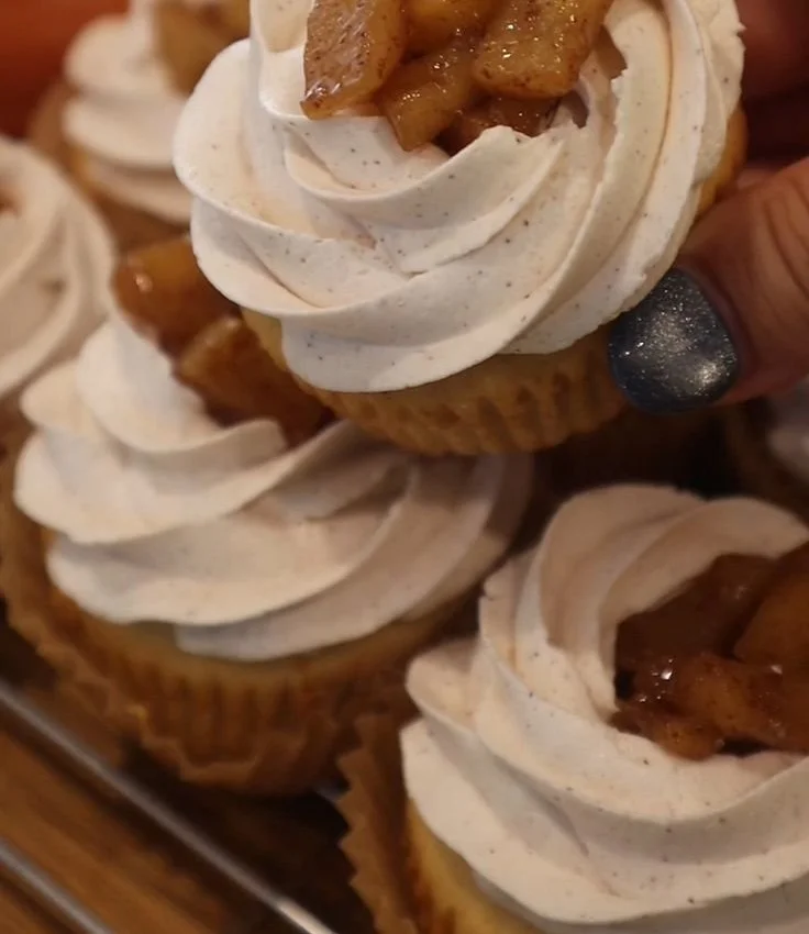 Delicious apple pie cupcakes topped with cinnamon frosting and apple slices.