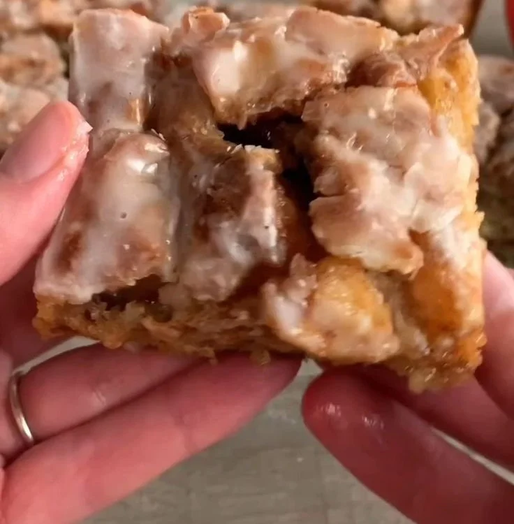 Slice of delicious cinnamon roll apple cake topped with frosting and cinnamon