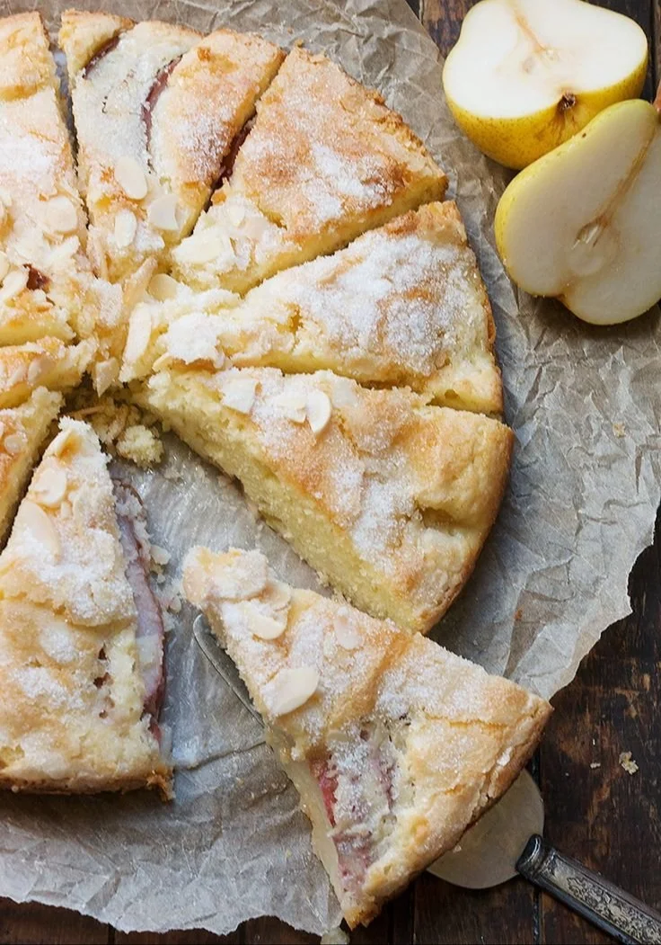 Sliced pear cake topped with crème fraîche and fresh pear slices