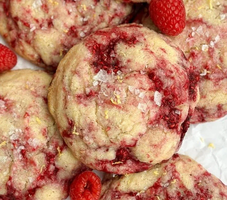 Zesty lemon raspberry cookies on a plate with fresh raspberries and lemon slices.