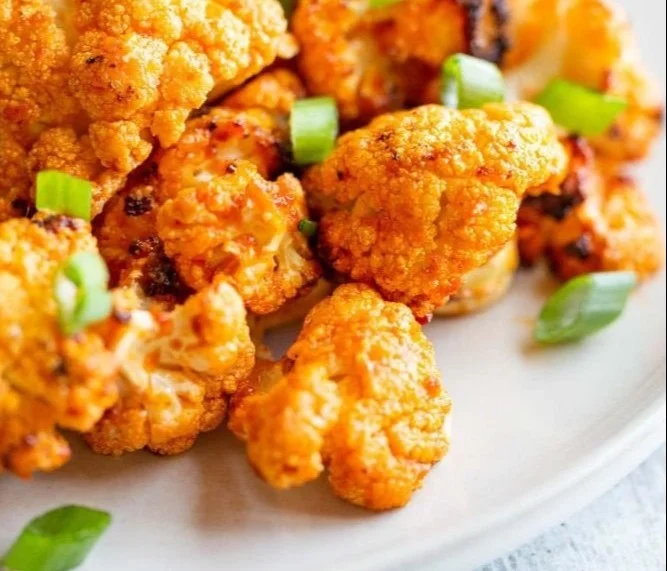 Air-fried buffalo cauliflower bites served with a side of dipping sauce