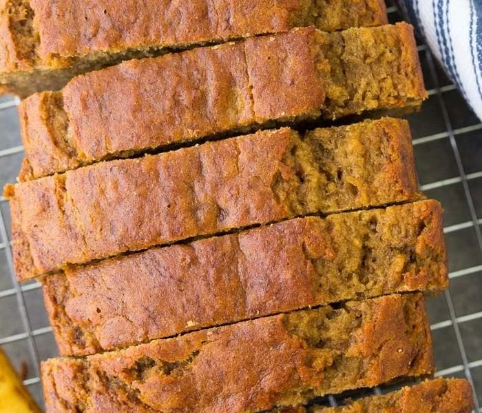 A slice of healthy banana bread with walnuts and bananas on a wooden table.