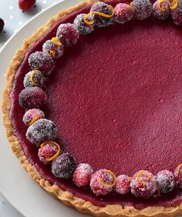 Delicious Cranberry Orange Curd Tart served on a white plate with orange slices