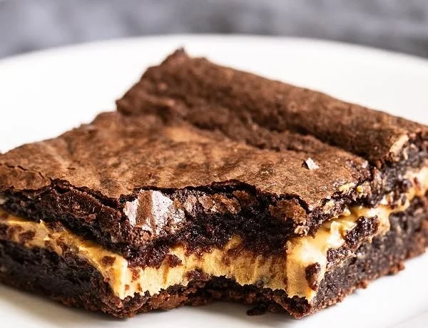 Creamy peanut butter stuffed brownies on a plate with chocolate drizzle