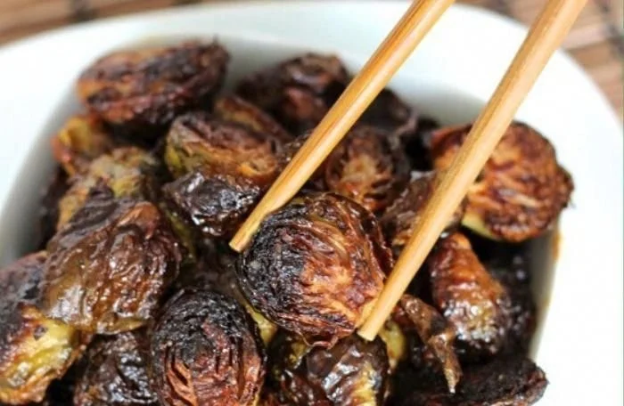 Bowl of crispy Asian Brussels sprouts garnished with sesame seeds and scallions