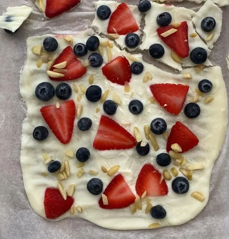 Frozen yogurt bark topped with fresh berries on a white plate.