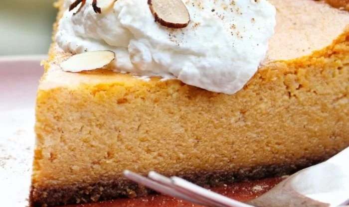 Slice of keto pumpkin cheesecake pie with whipped cream and pumpkin spice